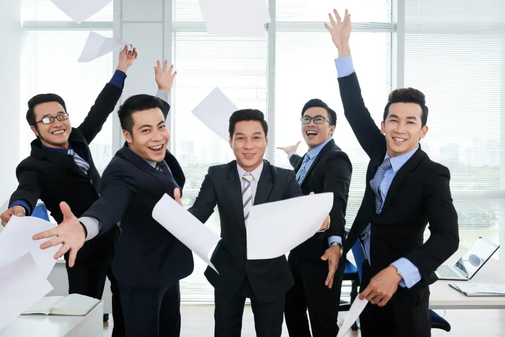 group cheerful asian businessmen suits throwing documents up air office (1)