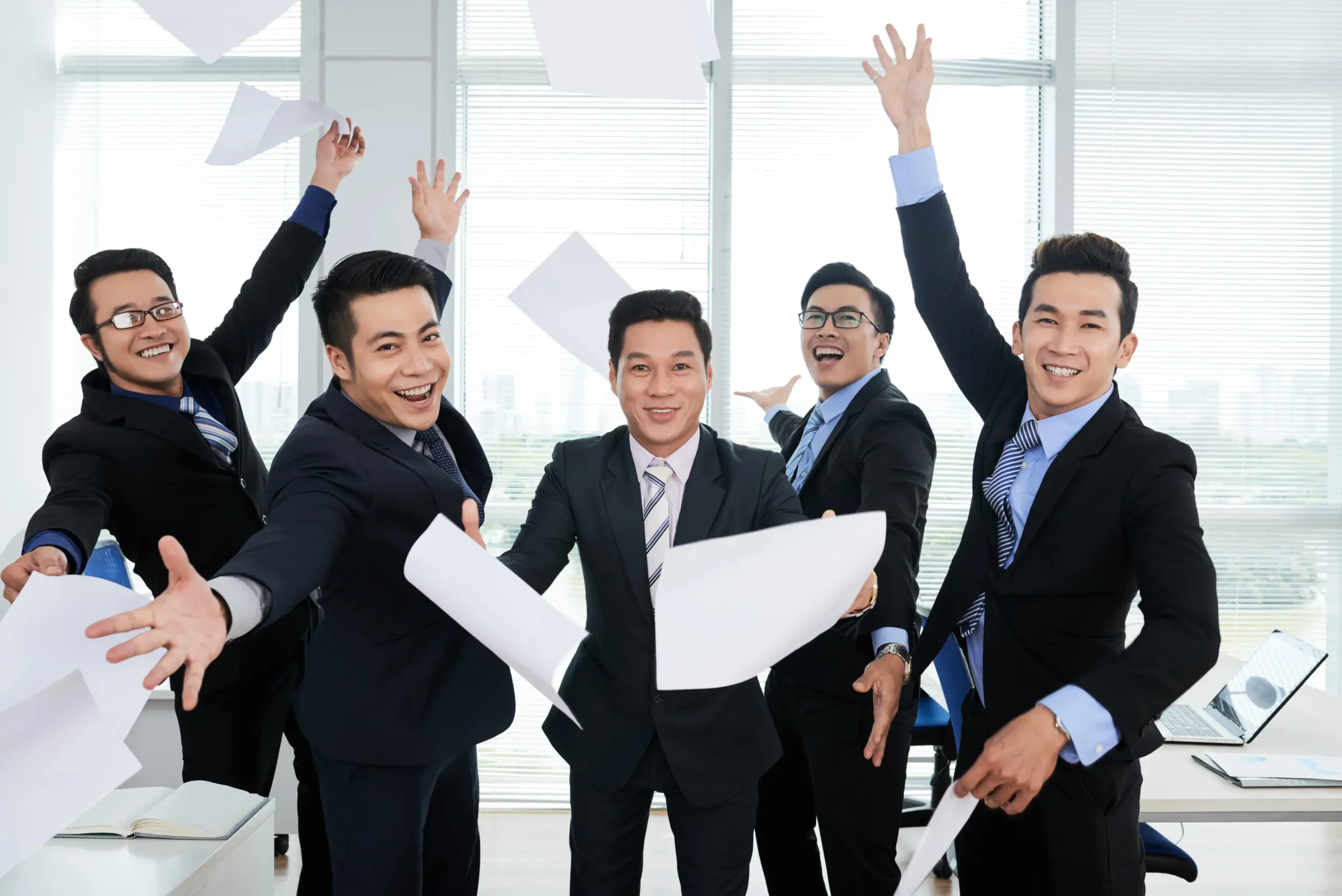 group cheerful asian businessmen suits throwing documents up air office (1)
