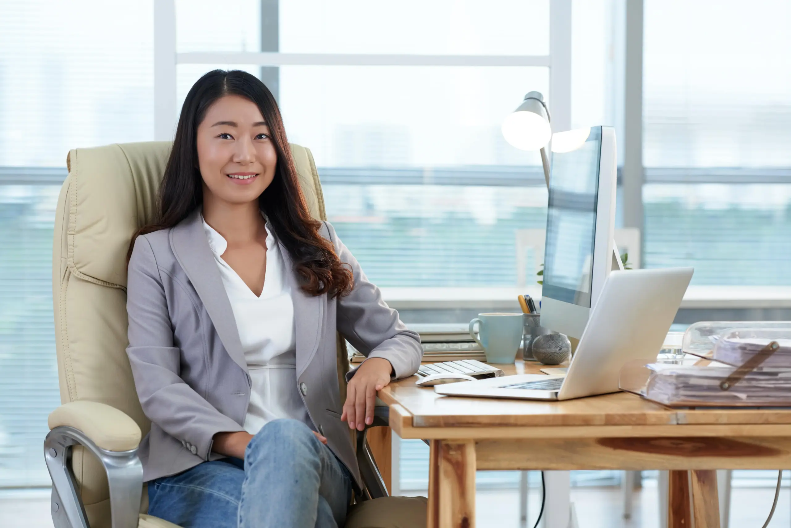 smartly dressed asian lady sitting office with computer laptop smiling (1)