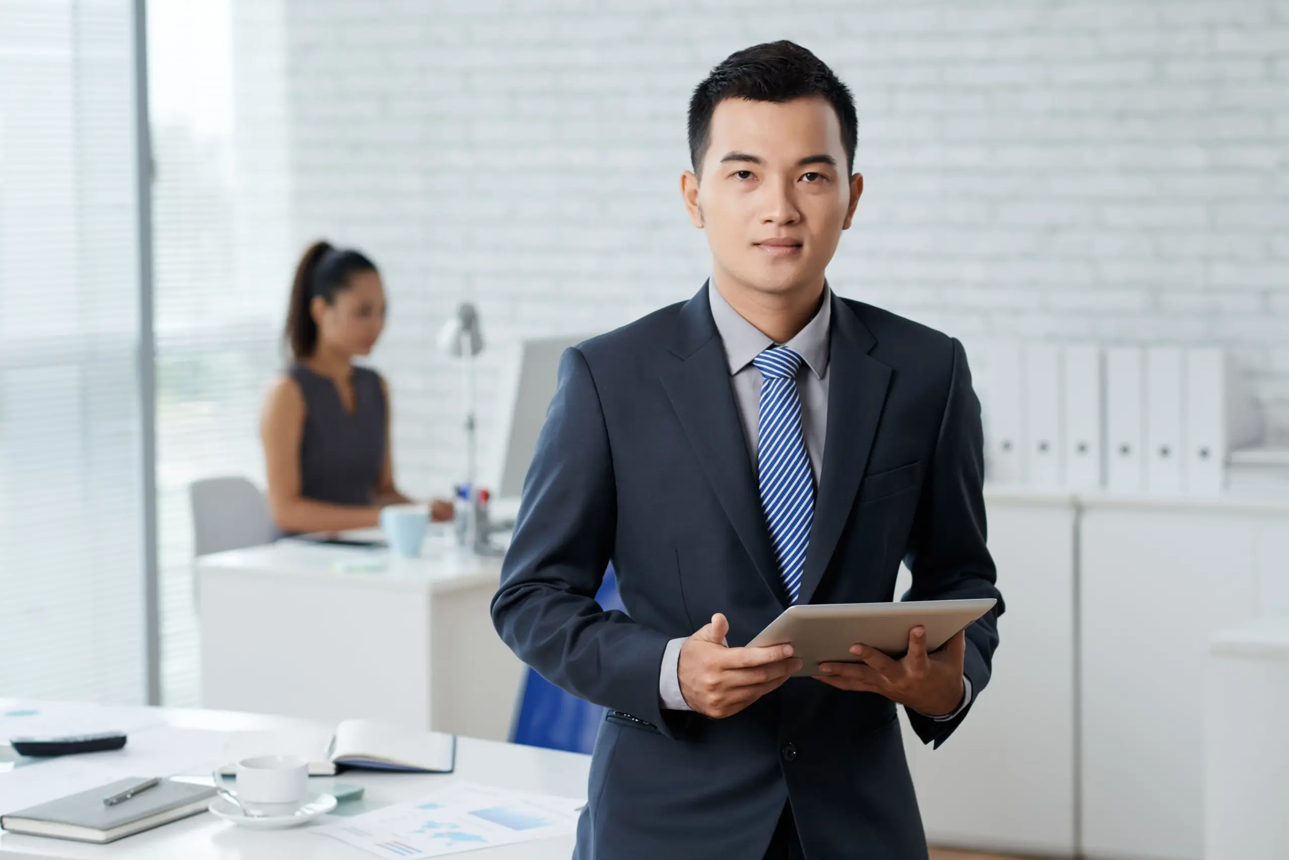 waistup shot asian business man standing moddle office holding digital tablet (1)