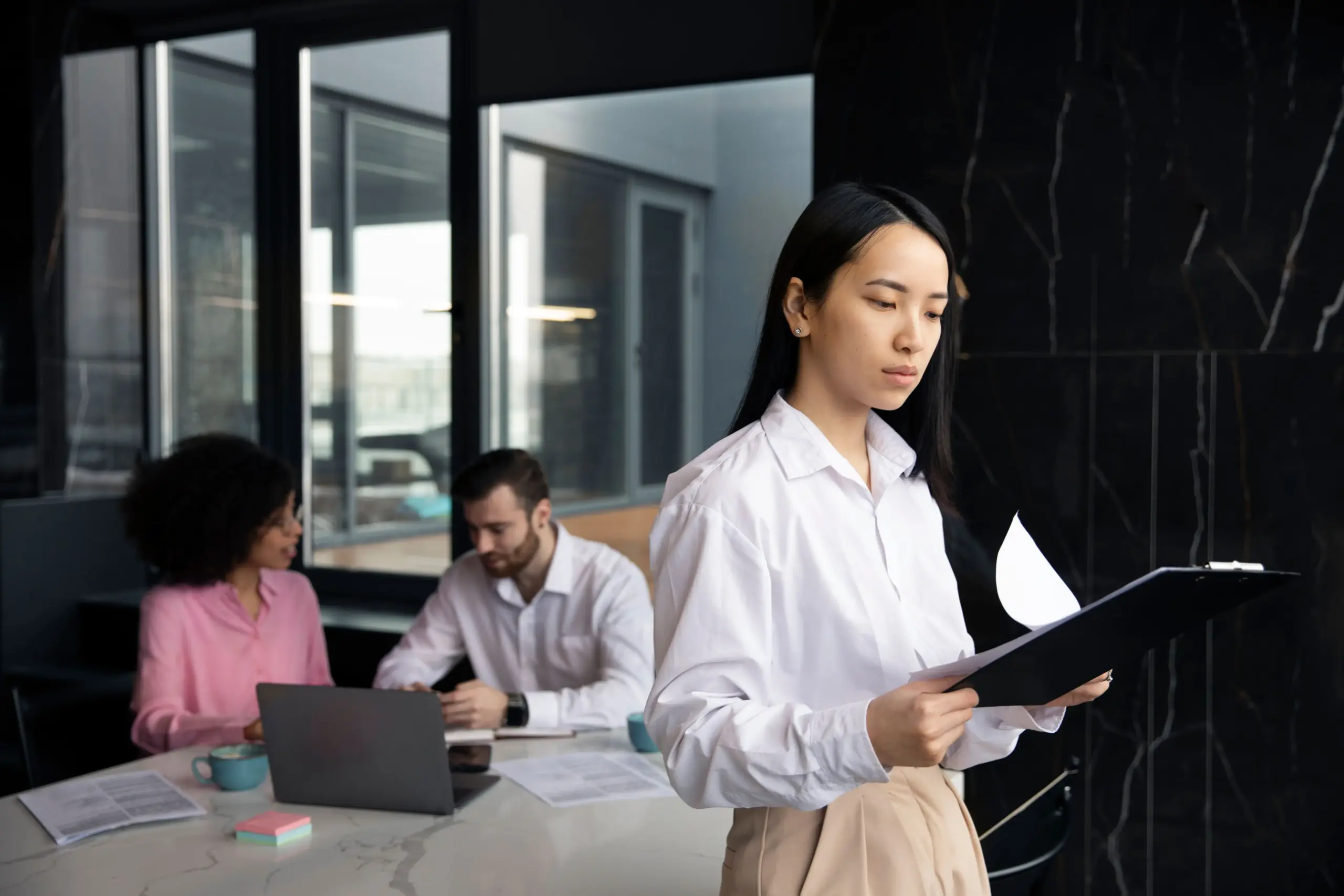 woman reading documents work while her colleagues are using laptop (1)
