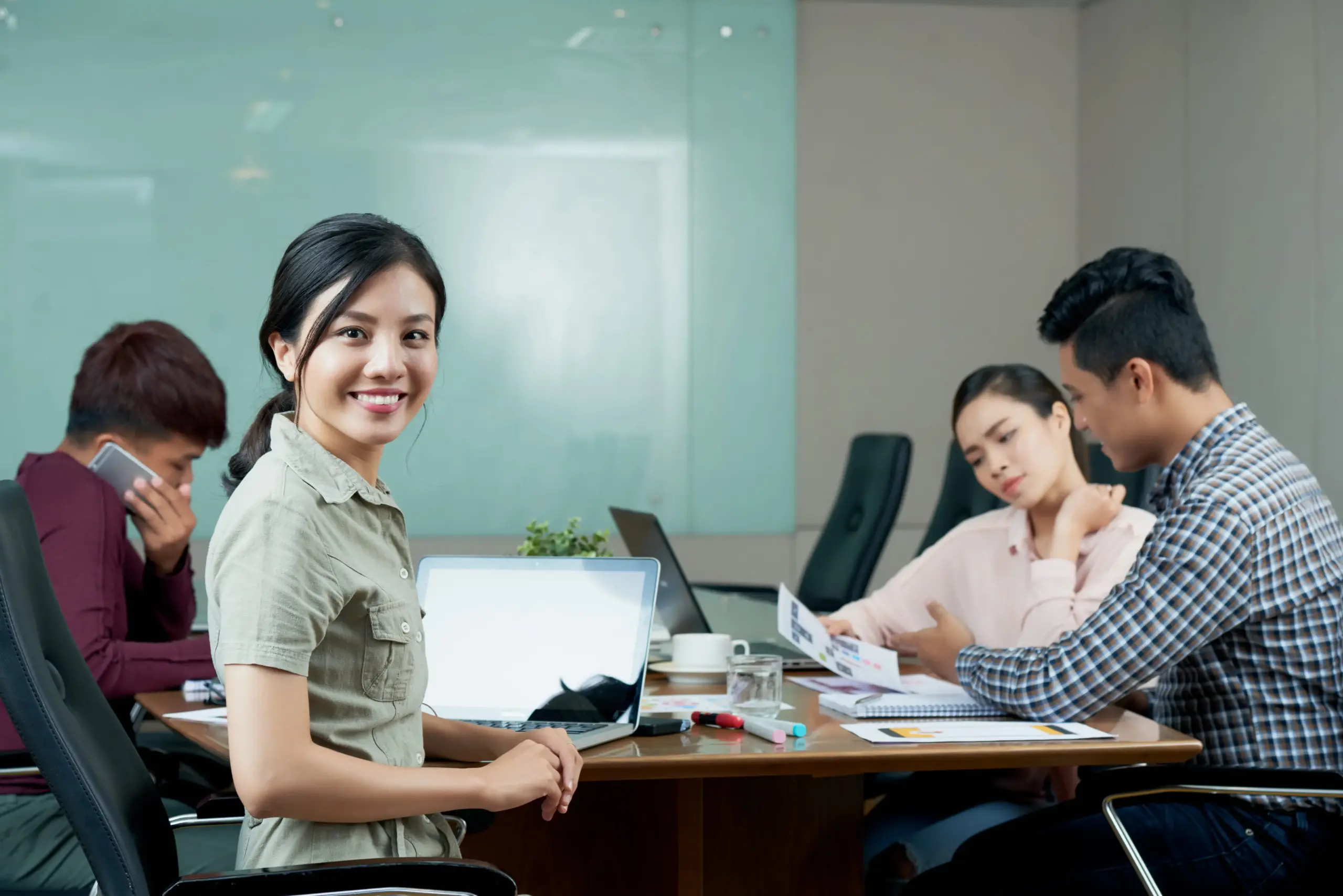 young woman looking camera distracted from departmental meeting with colleagues (1)