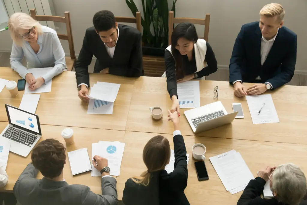 asian caucasian businesswomen handshaking group meeting top view (1)