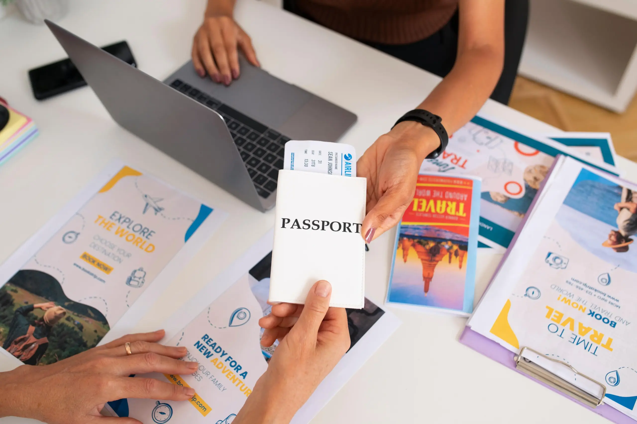 high angle travel agency desk with people working laptop holding passport (1)